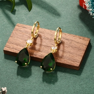 Close-up of emerald teardrop gemstone earrings with gold metal and zircon accents