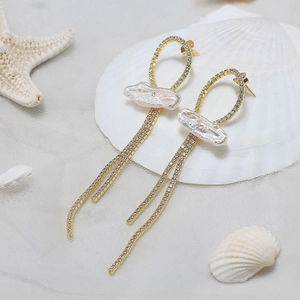 Detailed shot of golden tassel earrings with baroque pearls and sparkling zircon stones
