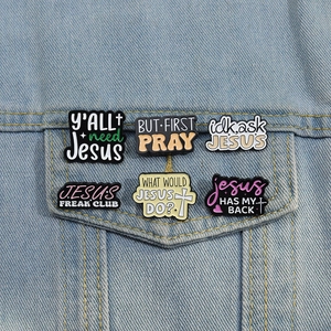 Set of 6 religious themed enamel pins and charms on a denim jacket pocket detail