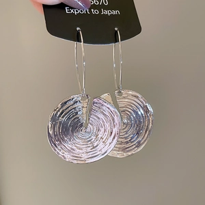 Detailed close-up of silver drop earrings featuring unique spiral hammered round charms