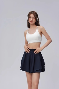 Détail du soutien-gorge de sport blanc et de la jupe de tennis plissée bleu foncé