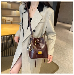 Dettaglio della borsa a secchiello in pelle bordeaux con coulisse e placca logo dorata