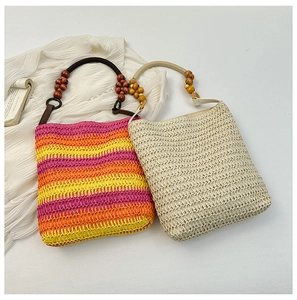 Detail of rainbow striped and beige straw bags with wooden bead handles on white fabric