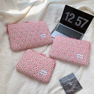 Three quilted pink floral laptop sleeves in different sizes on a soft white textured blanket