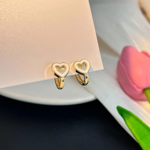 Détail rapproché de boucles d'oreilles cœur dorées avec perles sur carte blanche