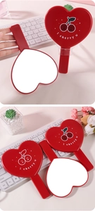 Vista dettagliata di specchi a mano a forma di cuore rosso con design a ciliegia