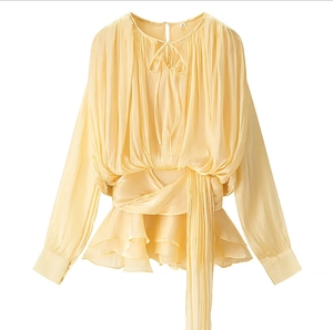 Detail of light yellow ruffle dress showing wrap waist tie and pleated chiffon fabric