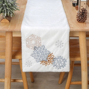 Détail d'un chemin de table en fausse fourrure blanche avec broderie de flocons de neige