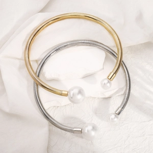 Close-up of gold and silver torque chokers with spiral metal tubes and white pearls