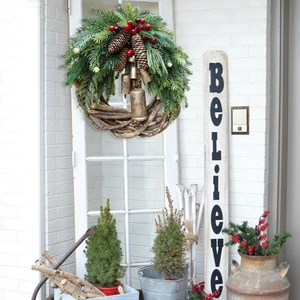 Detail of Christmas wreath with pine needles, cones, and vintage metal bells on a door