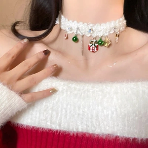 Gros plan du collier ras-du-cou de Noël avec cloches et étoiles sur dentelle blanche