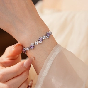 Close-up of a silver zircon bracelet with oval purple stones worn on a female wrist