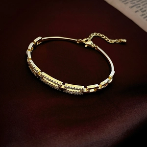 Detail of gold plated square zircon bracelet with lobster clasp on red velvet background
