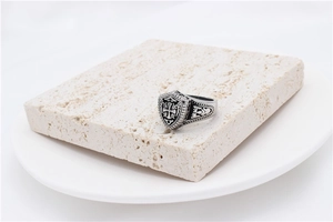 Macro shot of retro stainless steel knight shield ring with cross and scroll engraving