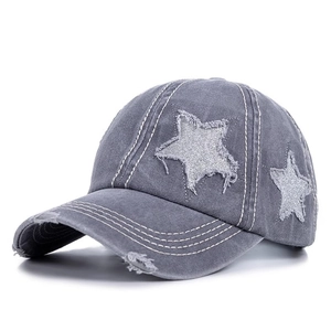 Detail of grey washed cotton baseball cap with distressed holes and sequin star patch