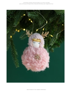 Pink plush angel Christmas ornament with reindeer antlers on a green pine branch