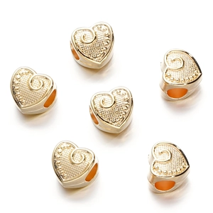 Macro shot of gold heart-shaped CCB beads with detailed relief patterns for DIY jewelry