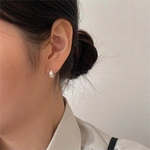 Close-up of minimalist silver water drop earrings with vertical textured stripe design