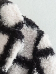 Close-up of the thick black and white checkerboard plush faux fur coat fabric texture