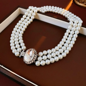 Dettaglio della collana di perle bianche a tre fili con chiusura a strass ovali