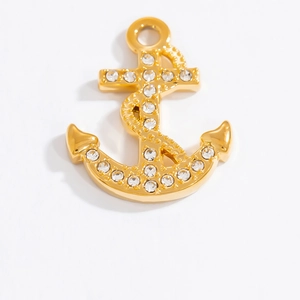 Vue macro d'un pendentif ancre doré orné de strass brillants sur fond blanc