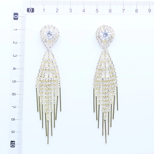 Detailed view of long gold tassel earrings with clear rhinestones and scale ruler