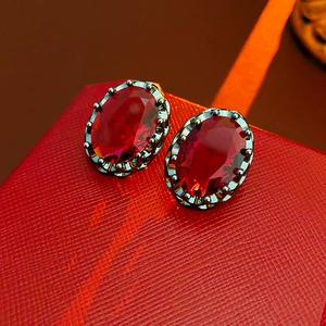 Macro shot of vintage oval red gemstone earrings with royal crown setting detail