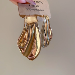 Detailed shot of golden fishtail stud earrings with high-gloss metallic finish on tag