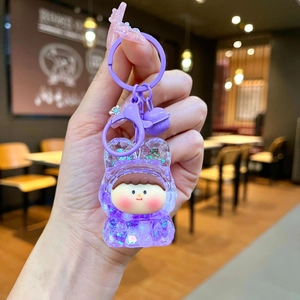 Close-up of purple acrylic liquid glitter keychain with cute bear hooded doll and bell