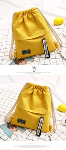 Macro shot of yellow canvas drawstring backpack with fashion label and zipper pocket