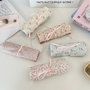 Flat lay of floral fabric makeup brush roll bags in five patterns with ribbon ties