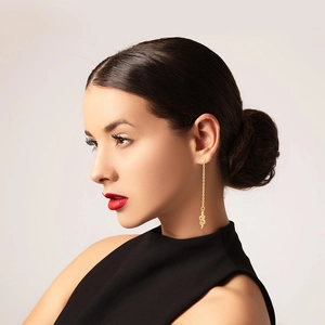 Detailed view of long gold snake-textured earrings on model with elegant drape