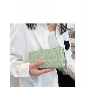Close-up of a light green quilted leather clutch with gold zipper and stitching detail