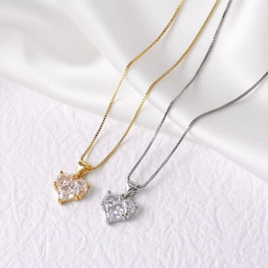 Gold and silver heart pendant necklaces with shimmering zircons on white fabric