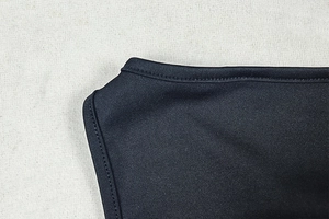 Detail of premium black knit fabric with precise double-needle hemming and clean stitching