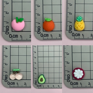 Detailed size comparison of resin fruit charms on a metric scale grid background