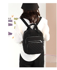 Detail of black nylon backpack with quilted diamond patterns and silver zippers on back