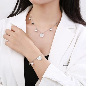 Silver titanium heart necklace and pearl bracelet set worn on a female model