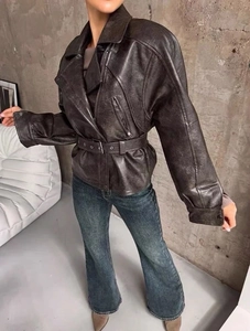 Macro detail of dark brown faux leather jacket with metal zipper and adjustable waist belt