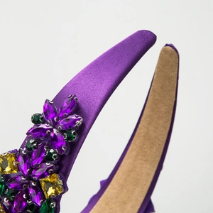 Detail of baroque headband with colorful rhinestones on purple satin fabric