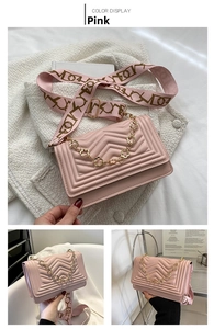 Detail of pink chevron quilted crossbody bag with floral chain and fabric strap