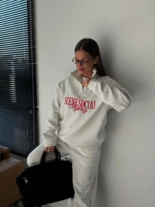 Close-up of red embroidered text on a grey fleece half-zip sweatshirt and pants set