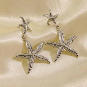 Starfish pendant earrings in polished stainless steel on elegant golden silk background