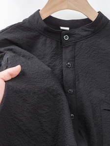Close-up of black waffle texture fabric on a men's stand collar polyester polo shirt