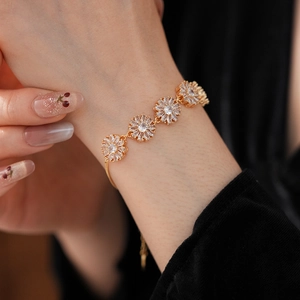 Detailed close-up of golden daisy flower bracelet with sparkling cubic zirconia on wrist