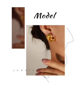 Detail of high-polish gold teardrop earrings with a modern curved design on model