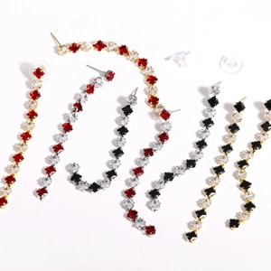 Macro detail of long tassel earrings featuring red black and white zircon stone settings