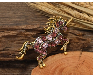Macro detail of retro gold unicorn brooch with colorful rhinestones and pink gems