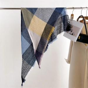 Detailed view of plaid scarf featuring blue, yellow, and grey patterns with soft fringes