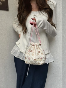Close-up of quilted drawstring bag with cartoon bear patterns and pink woven cords